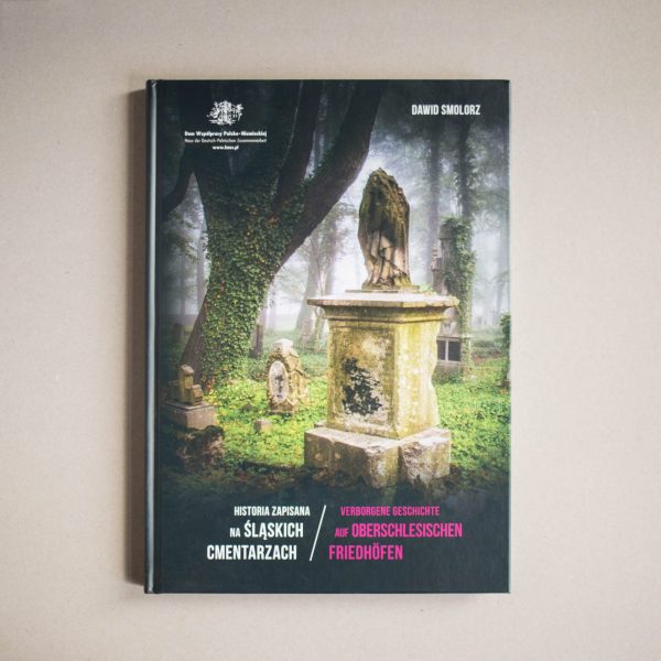 Leżąca książka Historia zapisana na śląskich cmentarzach. Na okładce zdjęcie kilku starych nagrobków porośniętych mchem. Z lewej strony pień drzewa porośnięty bluszczem.